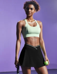 A woman dressed in IUGA Athletic Skorts in black, showcasing a high-waisted design and built-in compression shorts, perfect for pickleball and tennis.