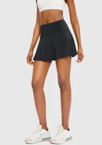 A model dressed in the SANTINY black pleated tennis skirt, highlighting its multiple pockets and built-in shorts for active performance.